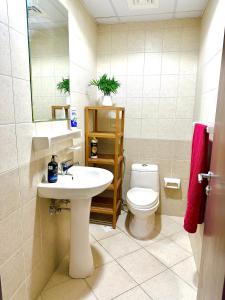 ein Badezimmer mit einem Waschbecken, einem WC und einem Spiegel in der Unterkunft Luxury Apartment 2 BR Al Majaz 2 view in Schardscha