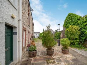 a courtyard with potted plants and a green door at 2 Bed in Cockermouth 87481 in Cockermouth