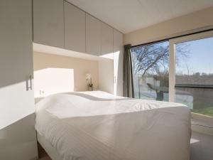 a bedroom with a white bed and a large window at Apartment Athene 002 with parking by Interhome in Bredene