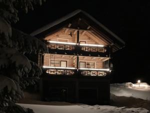 a wooden cabin with lights on the front at night at Holiday Home Täperän torppa by Interhome in Nilsiä
