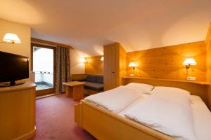 a bedroom with a large bed and a flat screen tv at Hotel Bergkranz in Mieders