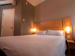 - une chambre avec un grand lit blanc et 2 oreillers dans l'établissement ibis Presidente Prudente Manoel Goulart, à Presidente Prudente
