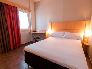 a hotel room with a large bed and a window at ibis Presidente Prudente Manoel Goulart in Presidente Prudente