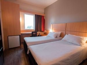 a hotel room with two beds and a window at ibis Presidente Prudente Manoel Goulart in Presidente Prudente