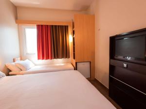 a hotel room with a bed and a flat screen tv at ibis Presidente Prudente Manoel Goulart in Presidente Prudente
