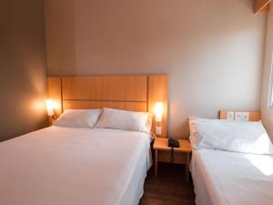 two beds in a hotel room with white sheets at ibis Presidente Prudente Manoel Goulart in Presidente Prudente