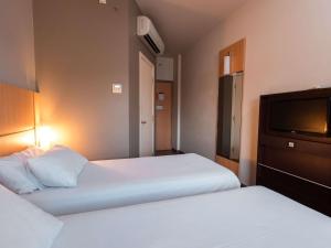 a hotel room with two beds and a flat screen tv at ibis Presidente Prudente Manoel Goulart in Presidente Prudente