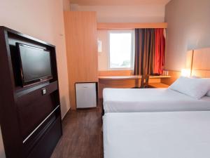 a hotel room with two beds and a flat screen tv at ibis Presidente Prudente Manoel Goulart in Presidente Prudente