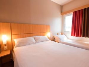 a bedroom with a large white bed and a window at ibis Presidente Prudente Manoel Goulart in Presidente Prudente