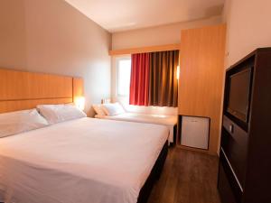 a hotel room with two beds and a television at ibis Presidente Prudente Manoel Goulart in Presidente Prudente