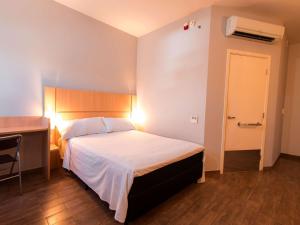 a bedroom with a bed and a desk and a door at ibis Presidente Prudente Manoel Goulart in Presidente Prudente