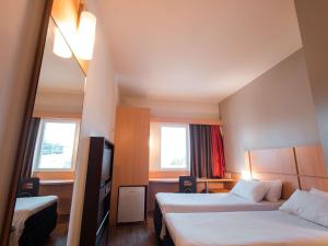 a hotel room with two beds and two windows at ibis Presidente Prudente Manoel Goulart in Presidente Prudente