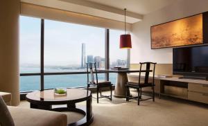 un soggiorno con tavolo, sedie e una grande finestra di Grand Hyatt Hong Kong a Hong Kong
