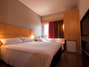 a hotel room with a large bed and a window at ibis Presidente Prudente Manoel Goulart in Presidente Prudente