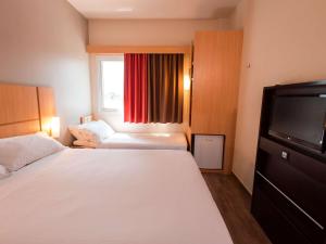 a hotel room with a bed and a television at ibis Presidente Prudente Manoel Goulart in Presidente Prudente