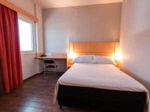 a bedroom with a bed and a desk and a window at ibis Presidente Prudente Manoel Goulart in Presidente Prudente