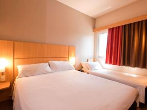 a hotel room with two beds and a window at ibis Presidente Prudente Manoel Goulart in Presidente Prudente