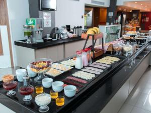 a buffet line with various food items on a counter at ibis Presidente Prudente Manoel Goulart in Presidente Prudente