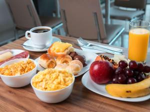 a table with plates of breakfast foods and a cup of coffee at ibis Presidente Prudente Manoel Goulart in Presidente Prudente