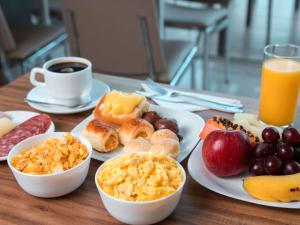 a table topped with plates of breakfast foods and orange juice at ibis Presidente Prudente Manoel Goulart in Presidente Prudente