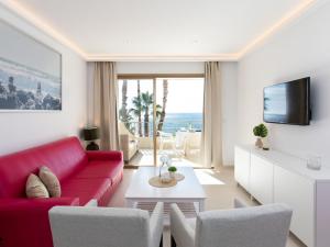 a living room with a red couch and a tv at Apartment Balcón de Cotobro I by Interhome in Almuñécar