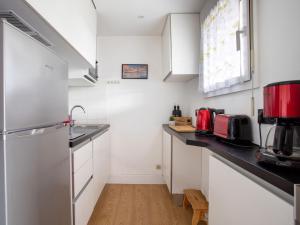 a kitchen with white cabinets and a red appliance at Studio Tivoli des Anges by Interhome in Villeneuve-Loubet