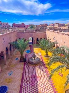 a courtyard with a fountain and palm trees in a building at Riad Les Roches Merzouga in Merzouga