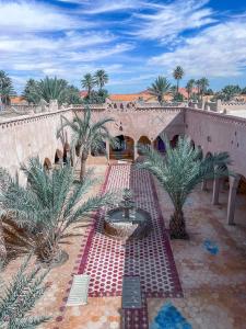 un ponte con fontana in un cortile con palme di Riad Les Roches Merzouga a Merzouga