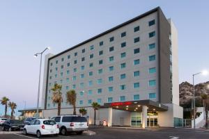 ein großes Gebäude mit Autos auf einem Parkplatz in der Unterkunft Hampton Inn by Hilton Hermosillo in Hermosillo