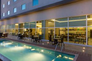 - une piscine avec des tables et des chaises à côté d'un bâtiment dans l'établissement Hampton Inn by Hilton Hermosillo, à Hermosillo