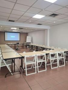 une grande chambre avec des tables et des chaises et un écran de projection dans l'établissement Ibis Budget Toulon Centre, à Toulon