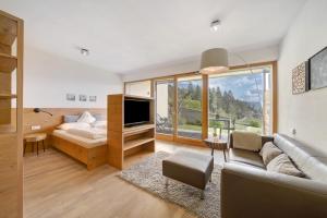 een woonkamer met een bank en een groot raam bij Dahoam - Apartment Relaxsuite in Schenna