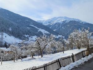 a snowy hill with trees and a fence and mountains at Apartment FeWo Anna by Interhome in Fliess
