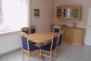 カロリーネンジールにあるFerienhaus Tovarのキッチン(木製テーブル、青い椅子付)