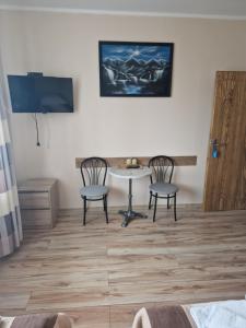 Pokój ze stołem, 2 krzesłami i telewizorem w obiekcie Willa AGAT w Ciechocinku