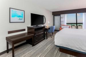 Habitación de hotel con cama y escritorio con TV. en Hampton Inn Fort Walton Beach, en Fort Walton Beach