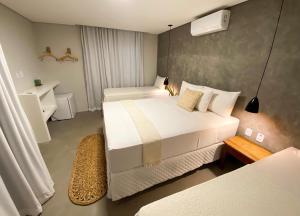 a hotel room with two beds and a bathroom at Pousada Baobá in Jericoacoara