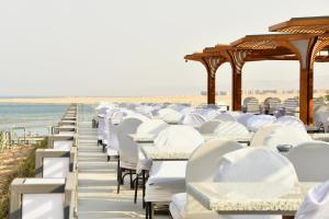 a row of white tables and chairs on the beach at SIRENA BEACH RESORT & SPA in Marsa Alam City