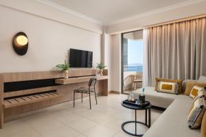 a living room with a couch and a table and a tv at Electra Palace Rhodes - Premium All Inclusive in Ialyssos