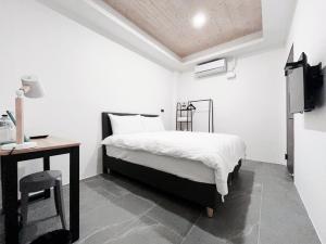 1 dormitorio con cama, mesa y escritorio en Xianqing Yizhi Homestay, en Taitung