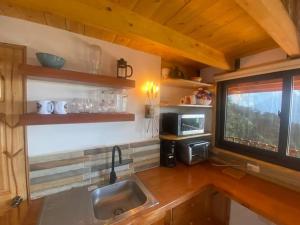 uma cozinha com um lavatório e uma janela num quarto em Hermosa Cabaña con vista a los volcanes 