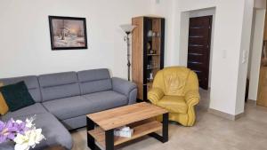 sala de estar con sofá y silla amarilla en Apartament Renii, en Tomaszów Mazowiecki