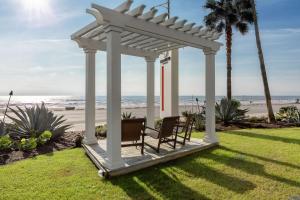 un cenador blanco con 2 sillas en el césped cerca de la playa en DoubleTree by Hilton Galveston Beach en Galveston