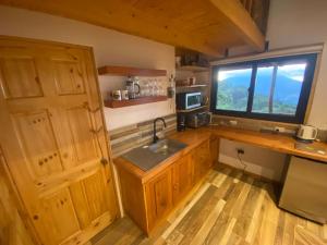 uma cozinha com um lavatório e uma grande janela em Hermosa Cabaña con vista a los volcanes 