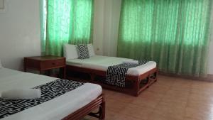 two beds in a room with green curtains at HMC Guesthouse - Malapascua Island Air-conditioned Room #2 in Logon