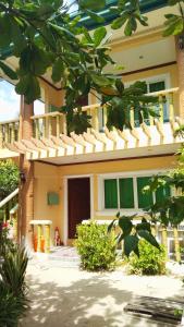 a building with a porch and a building with a fence at HMC Guesthouse - Malapascua Island Air-conditioned Room #2 in Logon