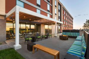 un patio con panche e tavoli e un edificio di Home2 Suites by Hilton Farmington/Bloomfield a Farmington