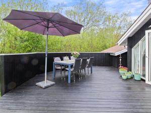 a patio with a table and an umbrella on a deck at Holiday Home Impi - 1-5km from the sea in Western Jutland by Interhome in Fanø