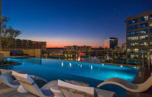 a large swimming pool with chairs and a city skyline at Embassy Suites by Hilton The Woodlands in The Woodlands