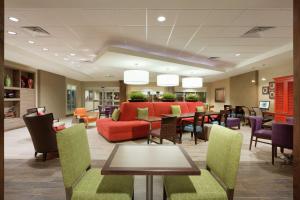 eine Hotellobby mit einem roten Sofa sowie Tischen und Stühlen in der Unterkunft Home2 Suites by Hilton Fort Smith in Fort Smith